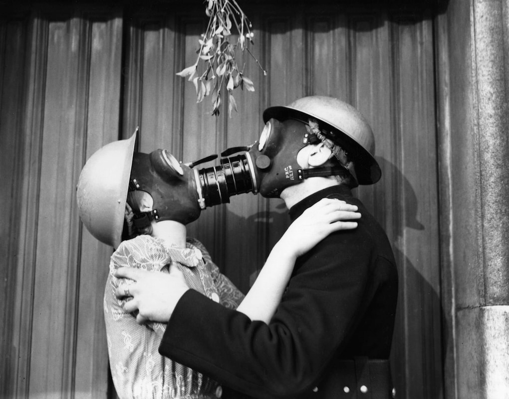 Kissing in gas masks under mistletoe / Cancelling Christmas, Hanukkah, Kwanzaa, Other Holidays / Karen McCann / EnjoyLivingAbroad.com